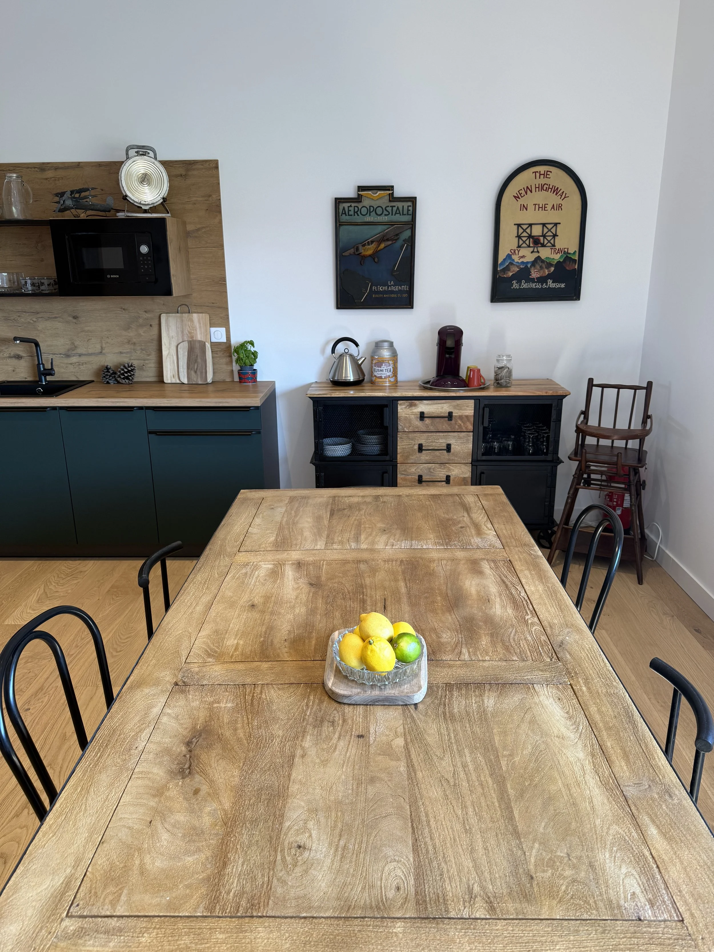 Table en bois avec un centre de fruits comprenant des citrons et un citron vert, dans une cuisine moderne avec un décor vintage.