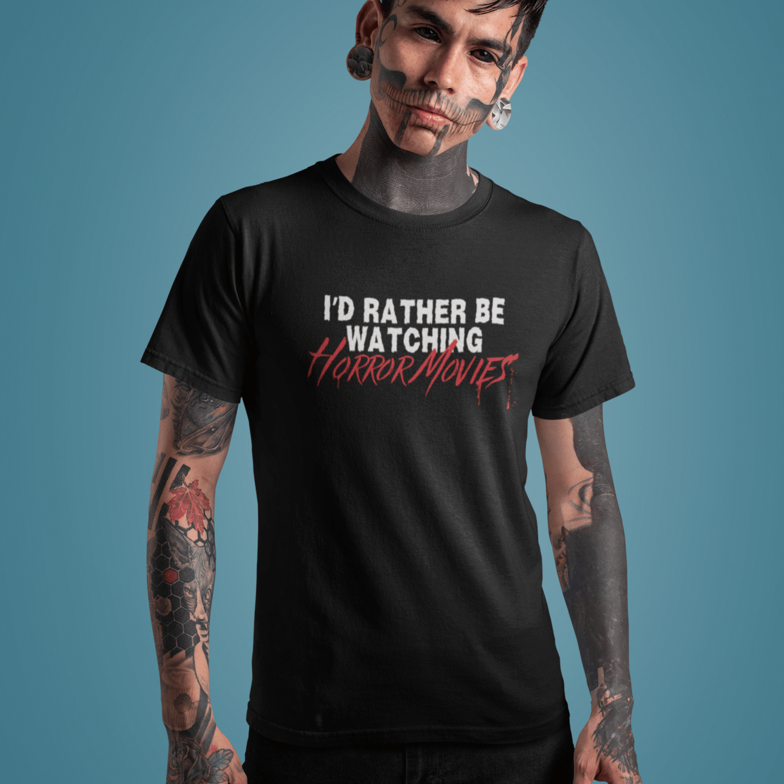 serious man with tattoos wearing horror movie t-shirt with text "I'd rather be watching horror movies"