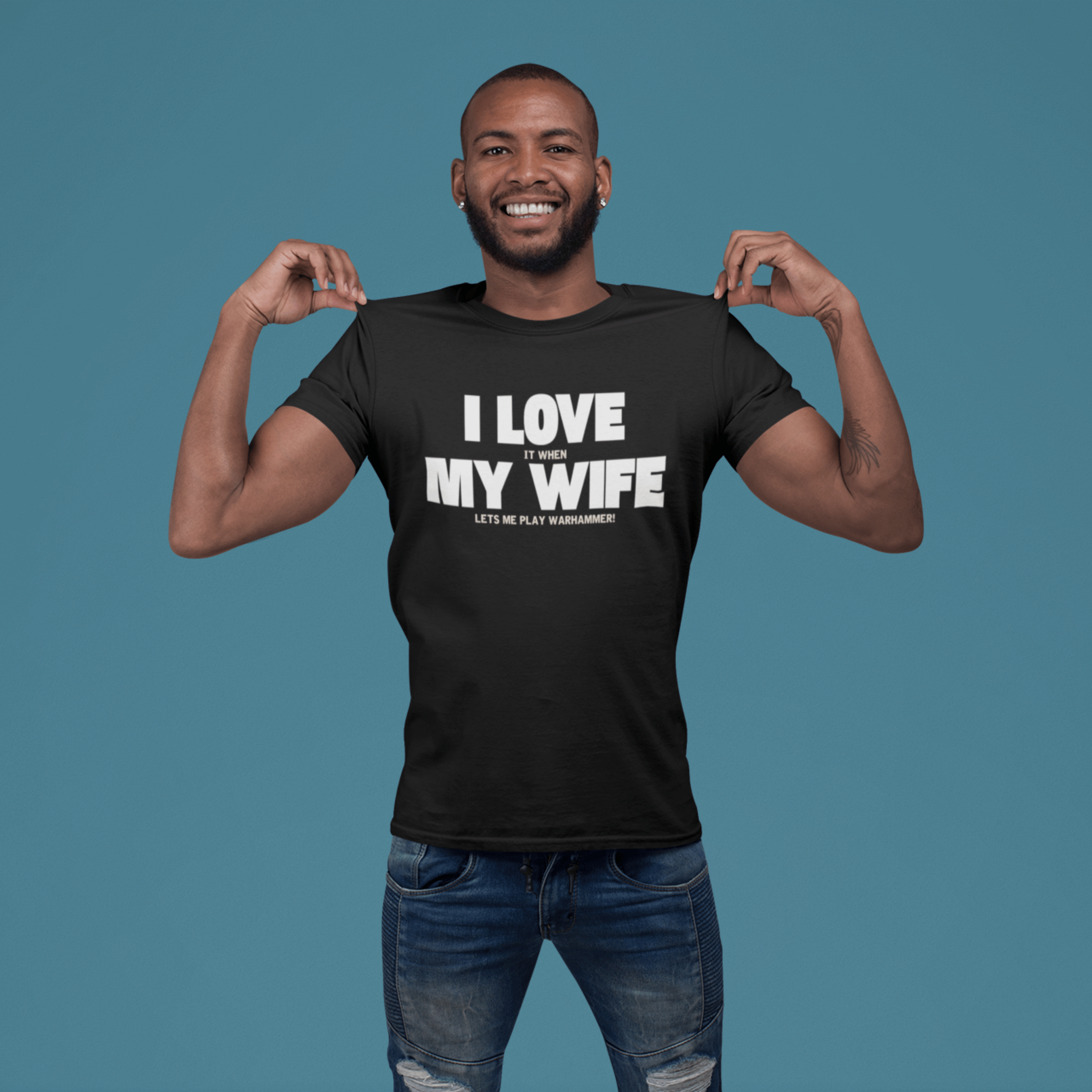 man pointing to Funny Warhammer t-shirt for husbands with wording "I love it when my wife lets me play warhammer!"