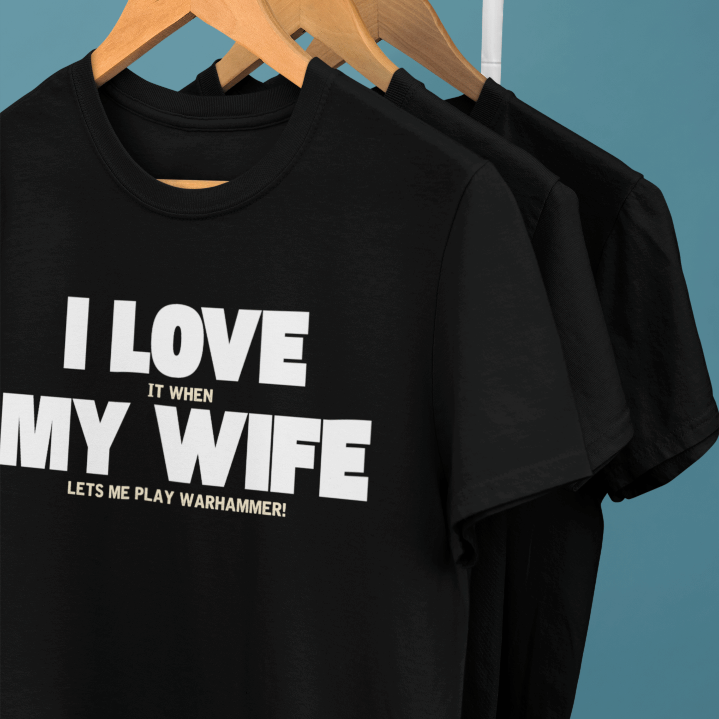 clothes rack of Funny Warhammer t-shirts for husbands with wording "I love it when my wife lets me play warhammer!"