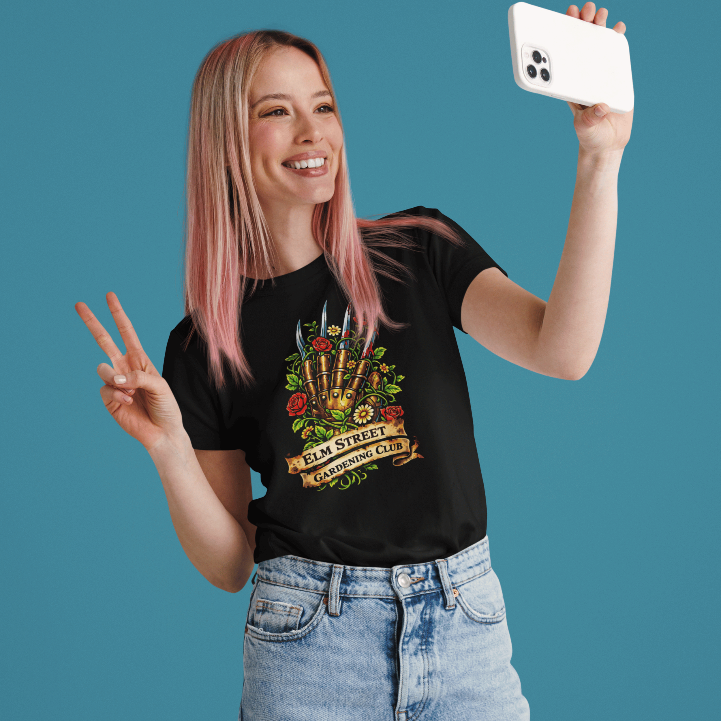woman taking selfie wearing Nightmare on Elm Street t-shirt with freddy's claw and "elm street gardening club" sign