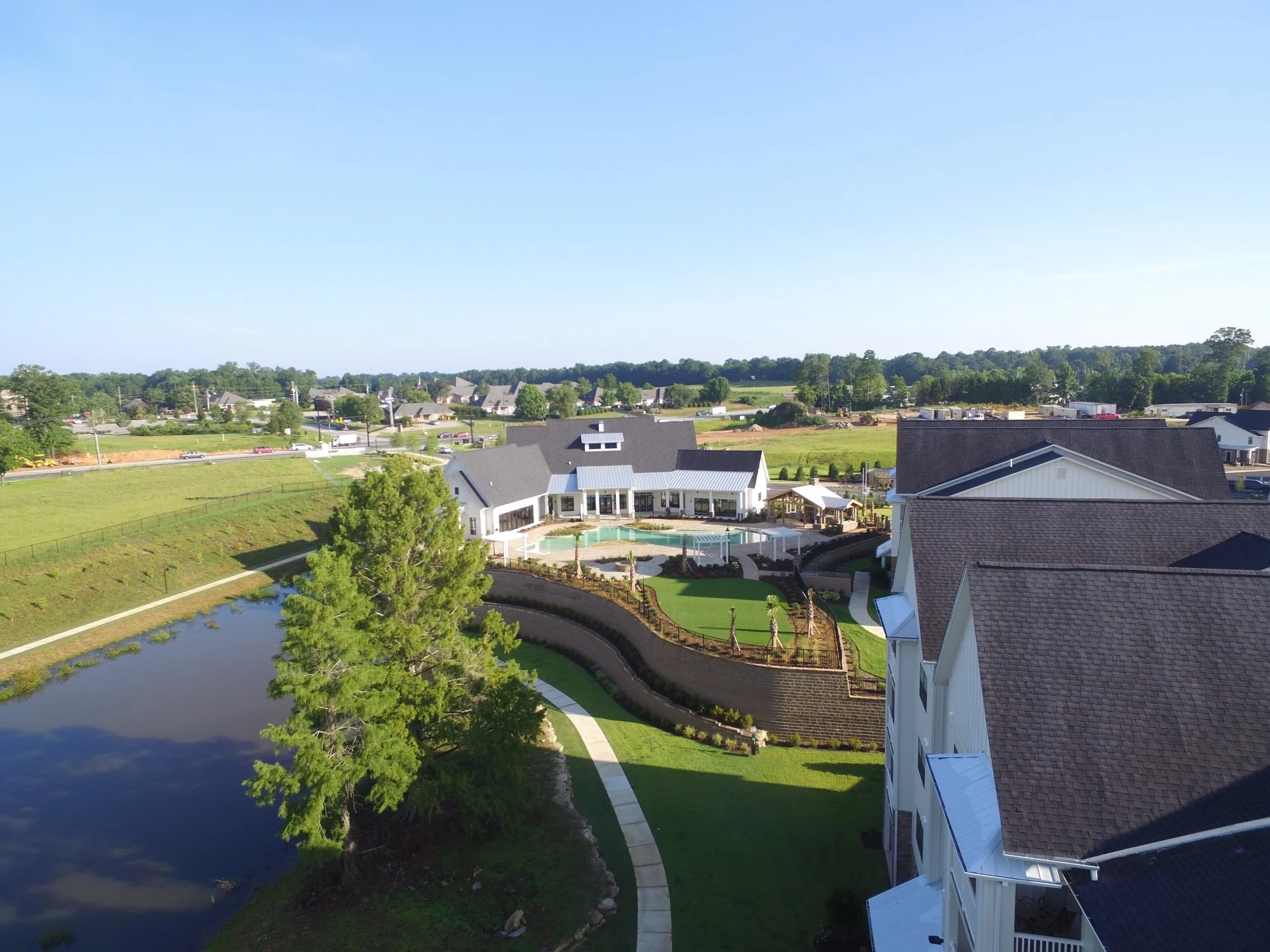 Drone shot over some rooftops and trees within The Glenn multifamily apartment complex - Auburn, AL
