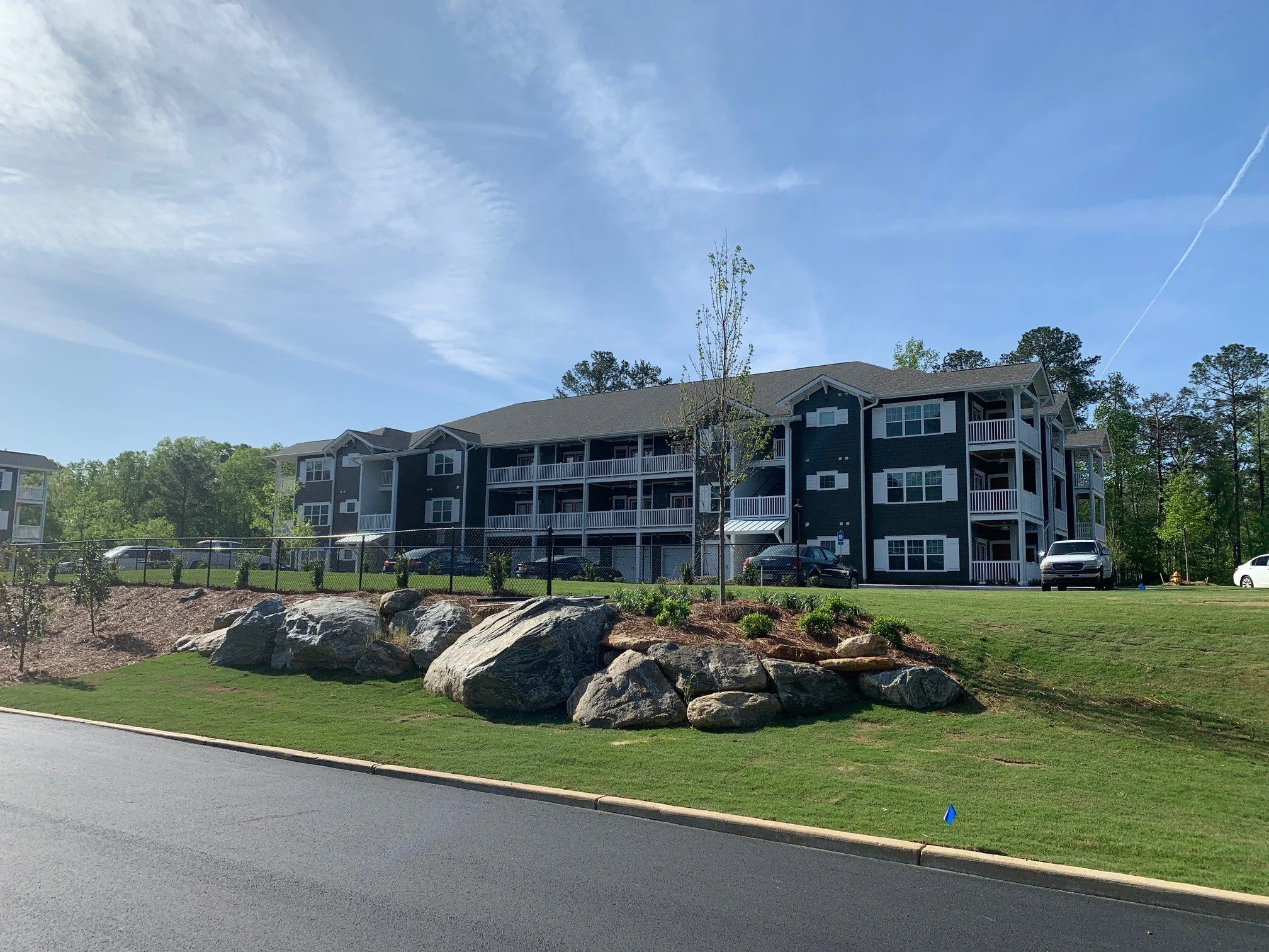 Multiple buildings with some large boulders and landscaping in the foreground at the Swallowtail Flats multifamily apartment complex - Columbus, GA