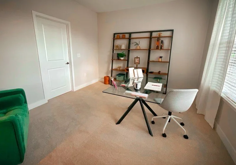 Office room with a large window, corner chair, and glass working table within the Courtney Ridge multifamily apartment complex - Charlotte, NC