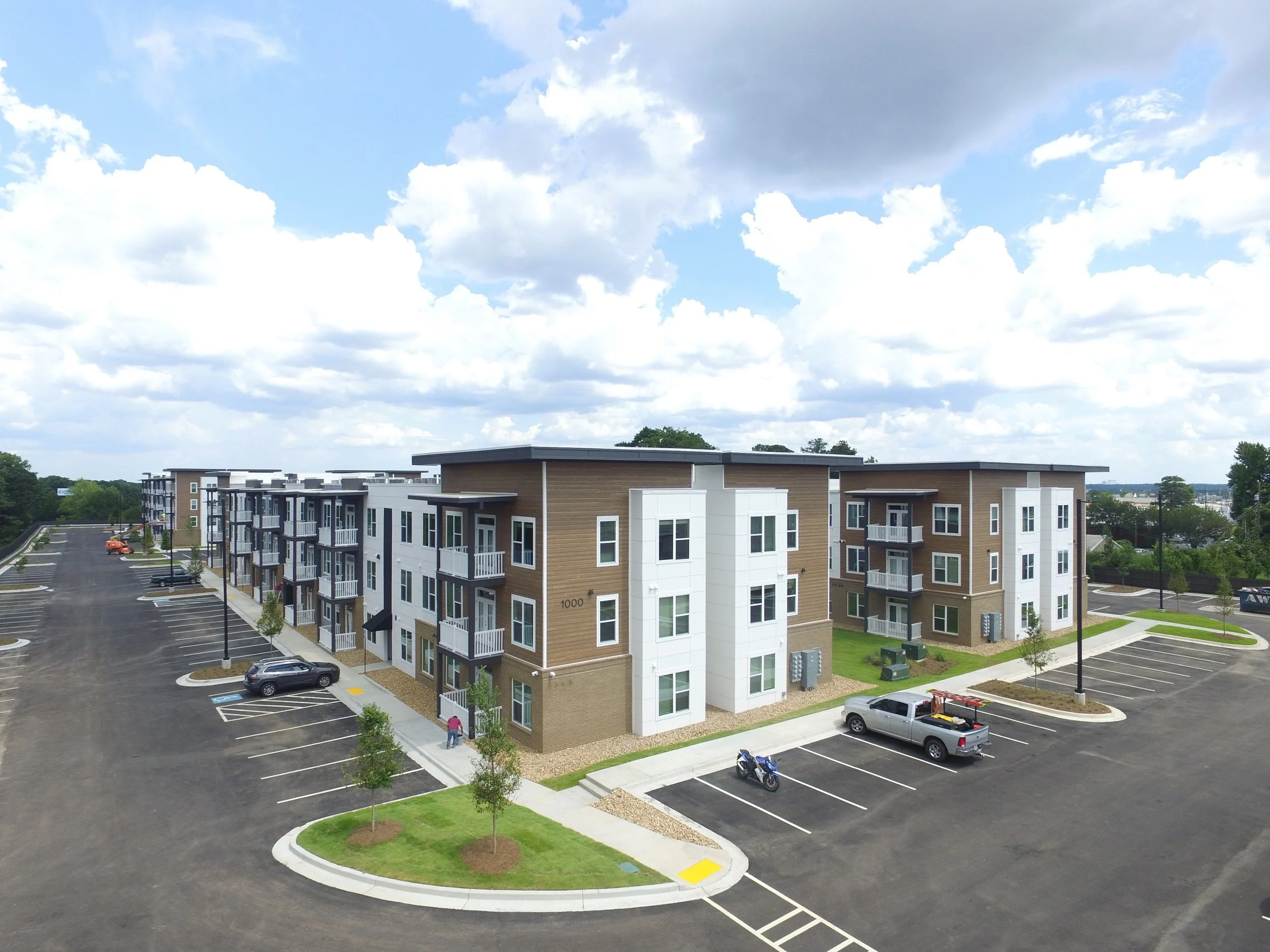 Overhead shot of several multifamily apartment buildings and the surrounding parking lot and some trees at The Beacon - Kennesaw, GA