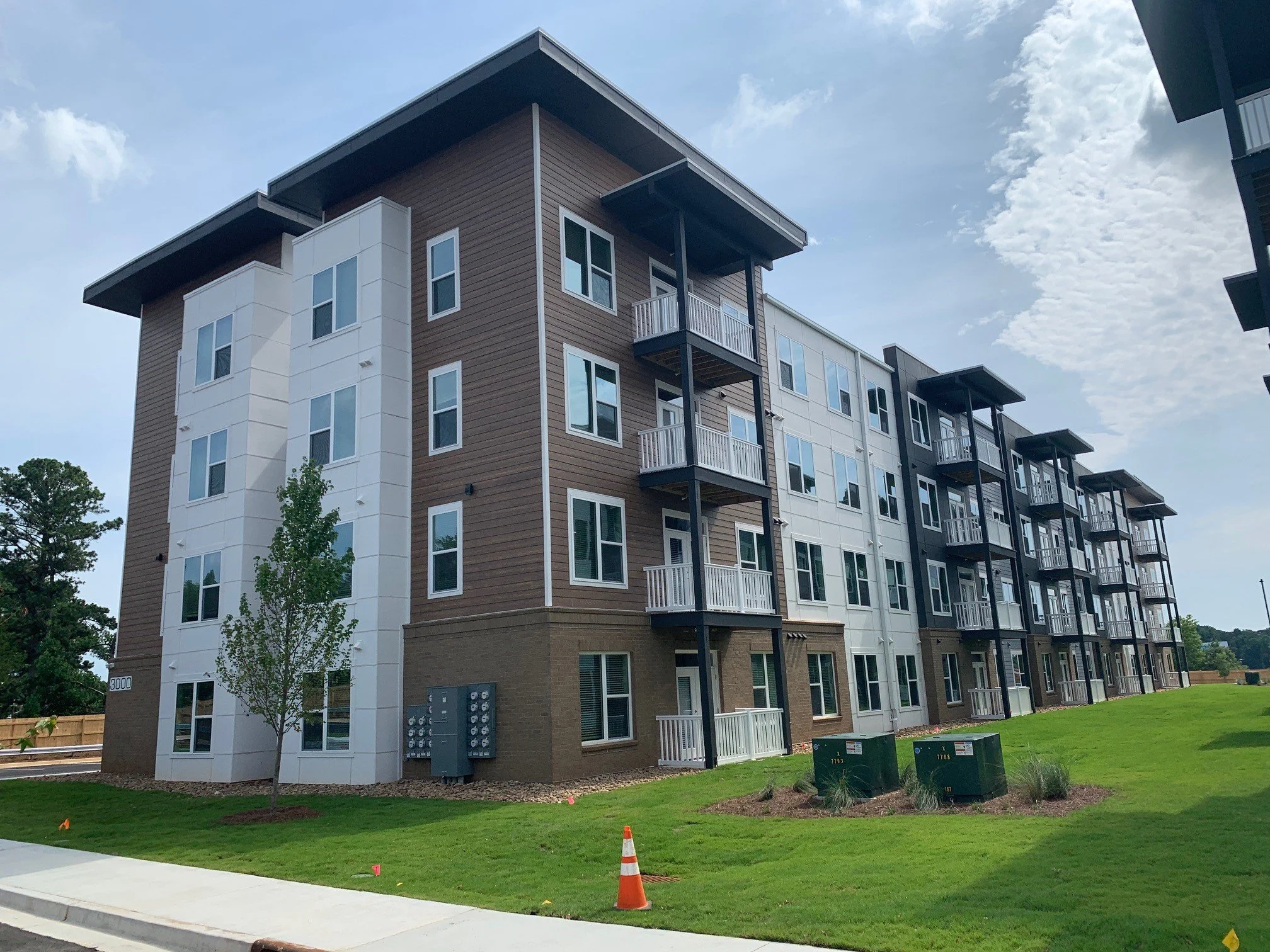 Multifamily apartment balconies and a small grassy courtyard on a warm summer day at The Beacon - Kennesaw, GA