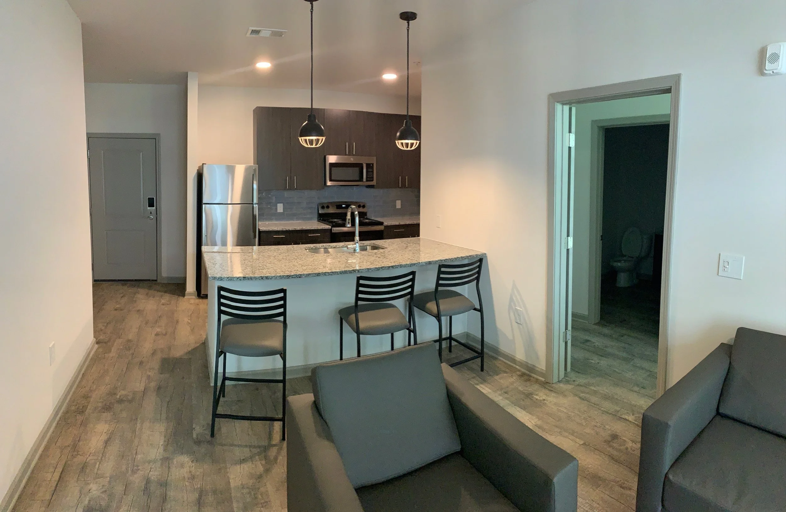 Wide-angle shot of a living room with a kitchen and island bar in a typical unit at The Beacon - Kennesaw, GA
