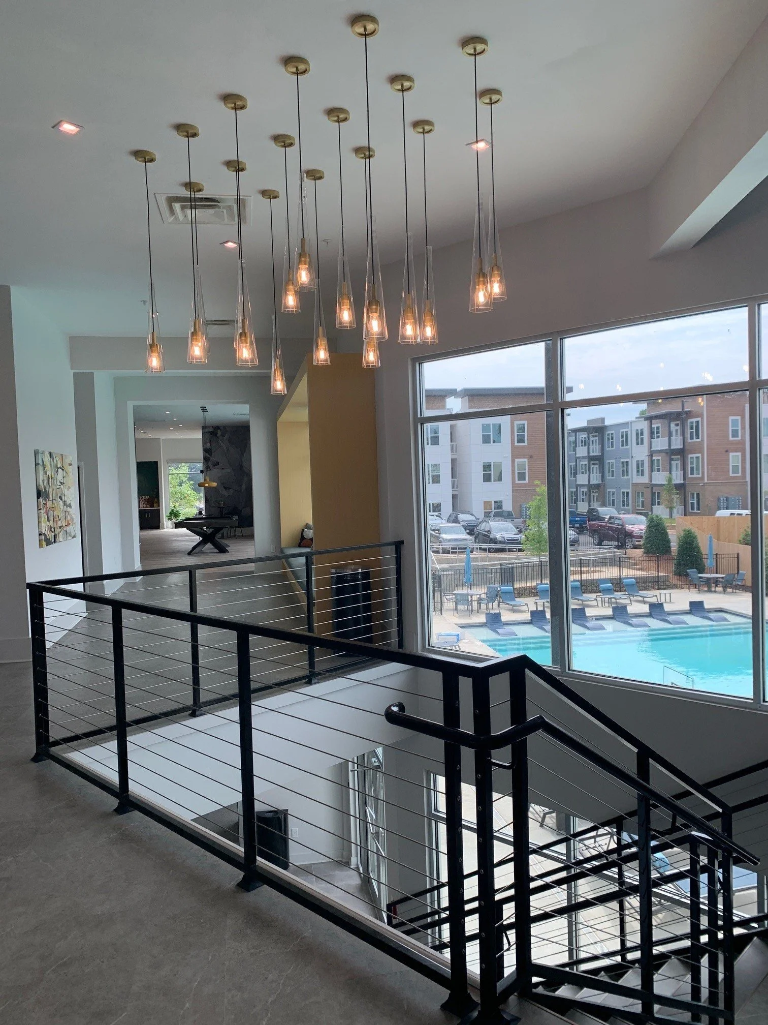 Upper stairway leading down to the commons area with a pool in the background, located at The Beacon - Kennesaw, GA