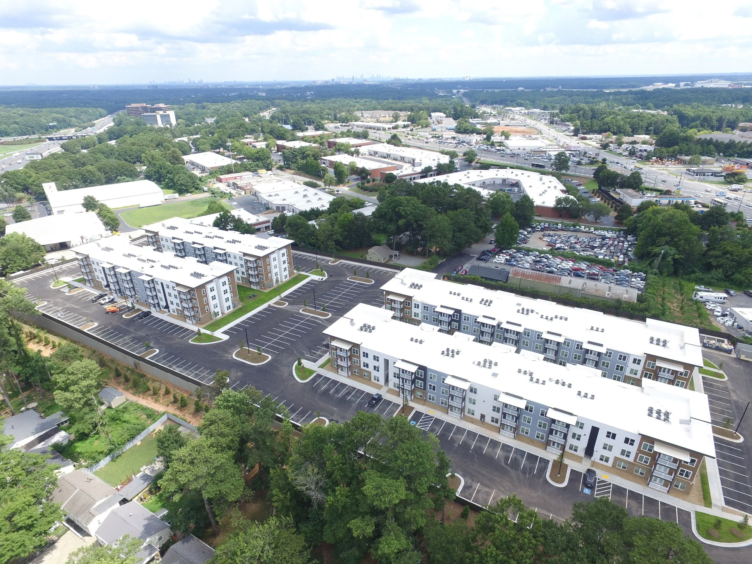 Overhead shot of several multifamily apartment buildings and the surrounding roads, trees and neighborhoods at The Beacon - Kennesaw, GA