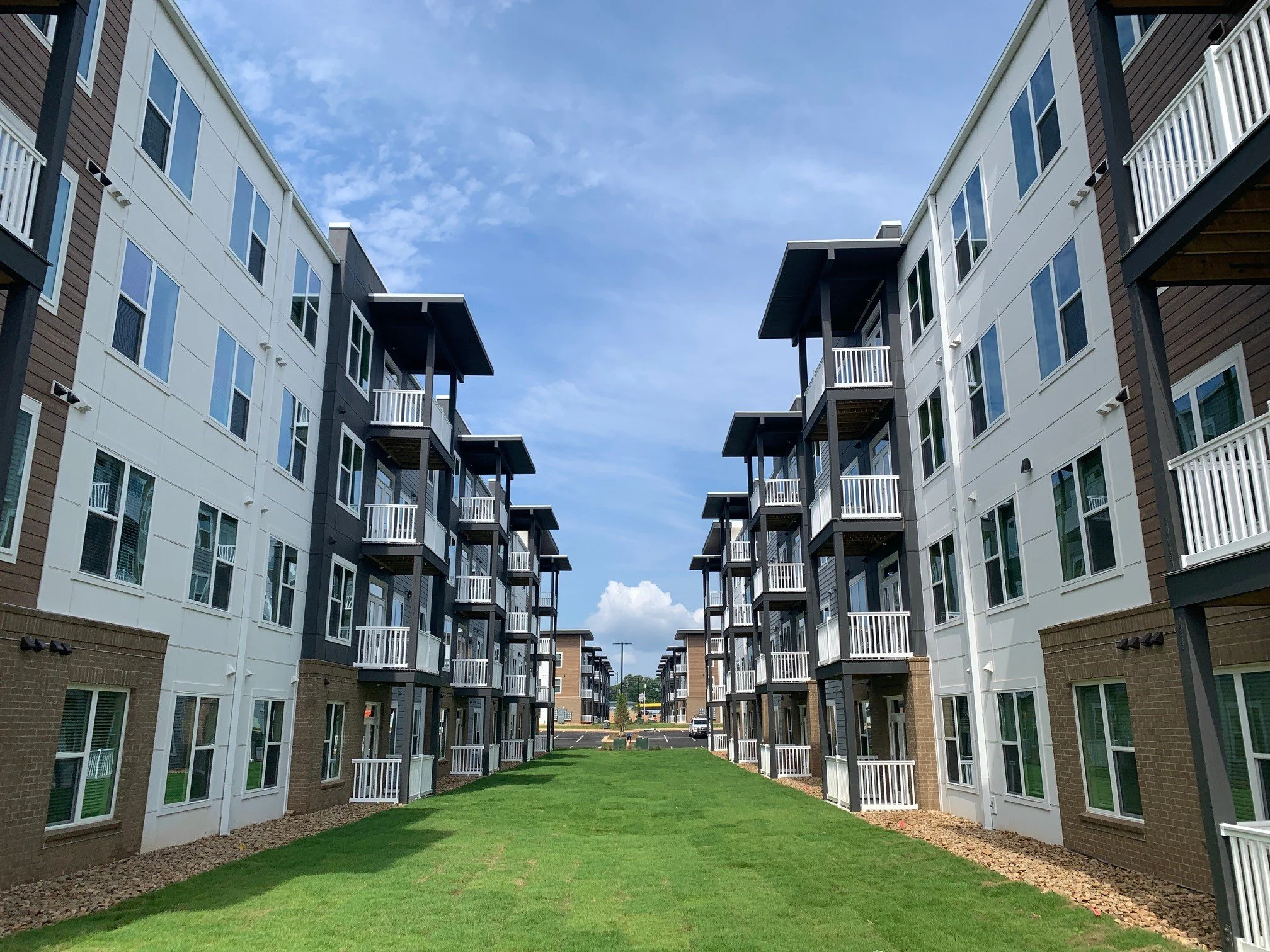 Multifamily apartment balconies and a small grassy courtyard on a warm summer day at The Beacon - Kennesaw, GA