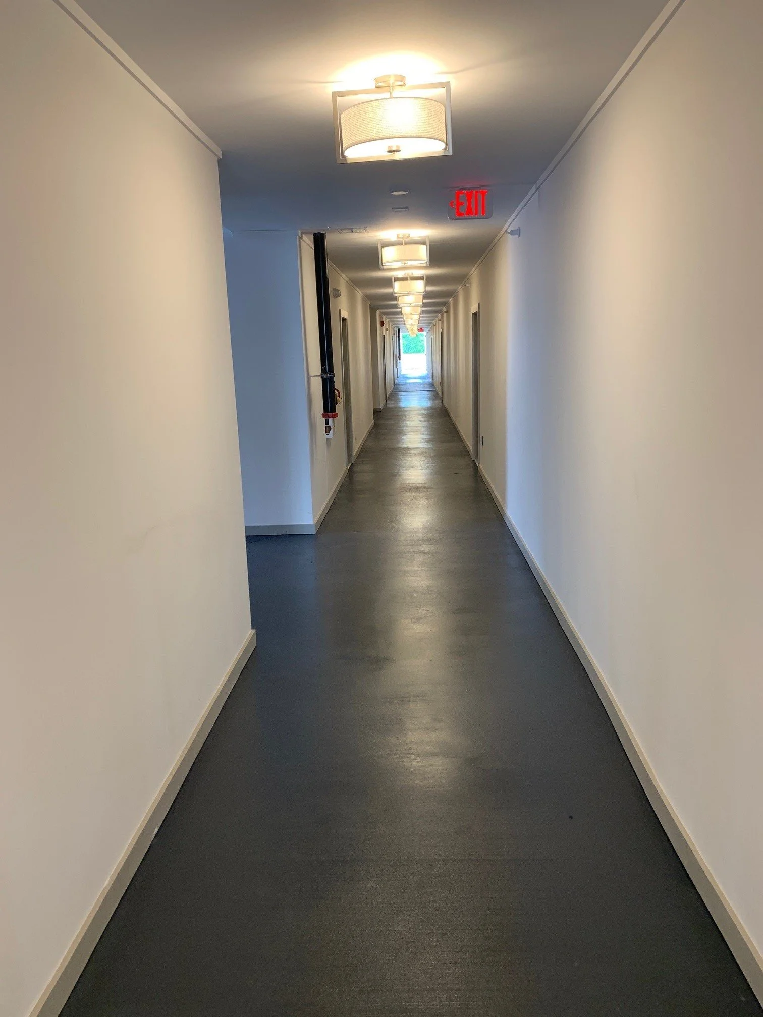 Long hallway with white walls and a concrete floor at The Beacon - Kennesaw, GA
