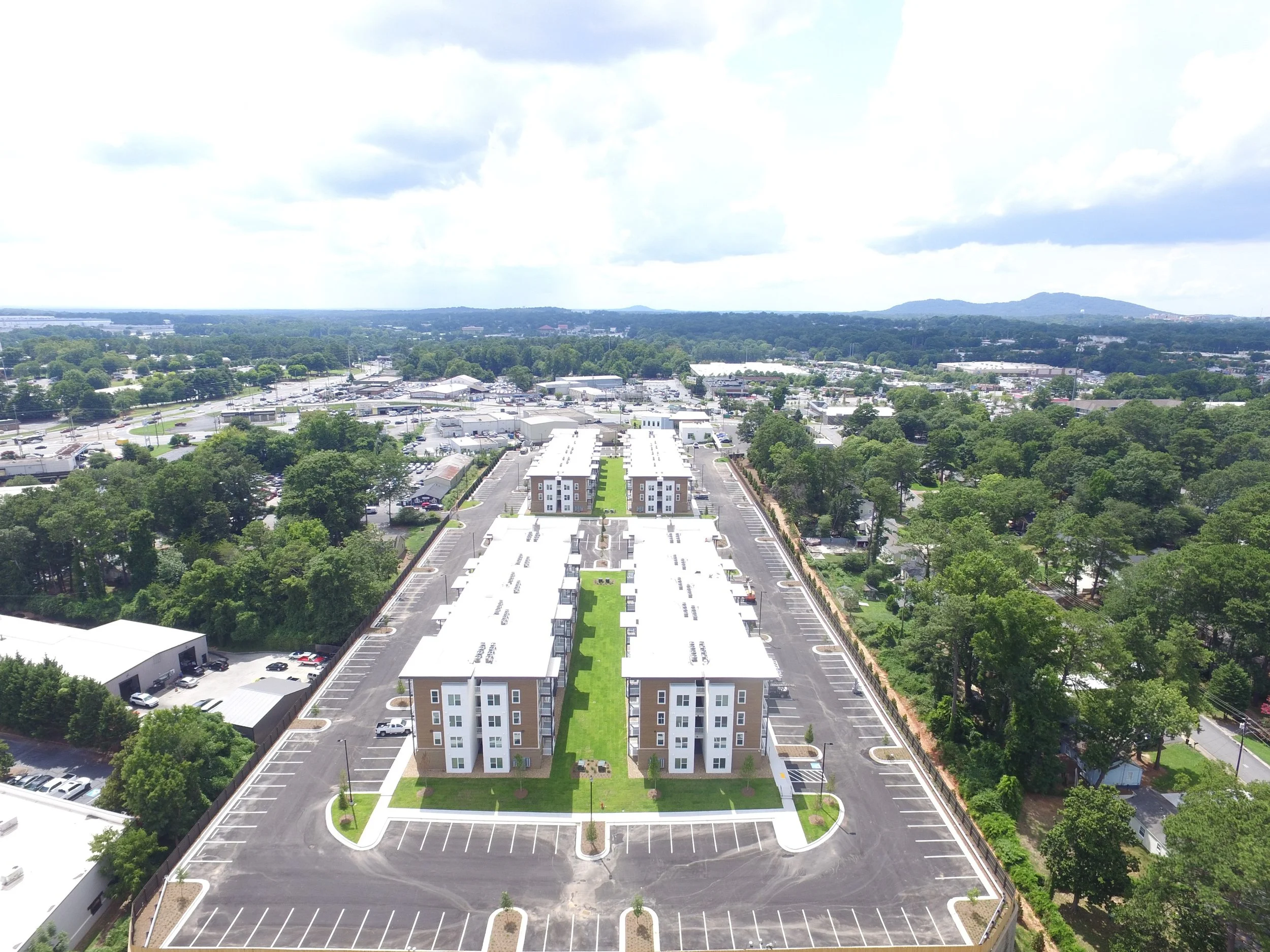 Overhead shot of several multifamily apartment buildings and the surrounding roads, trees and neighborhoods at The Beacon - Kennesaw, GA