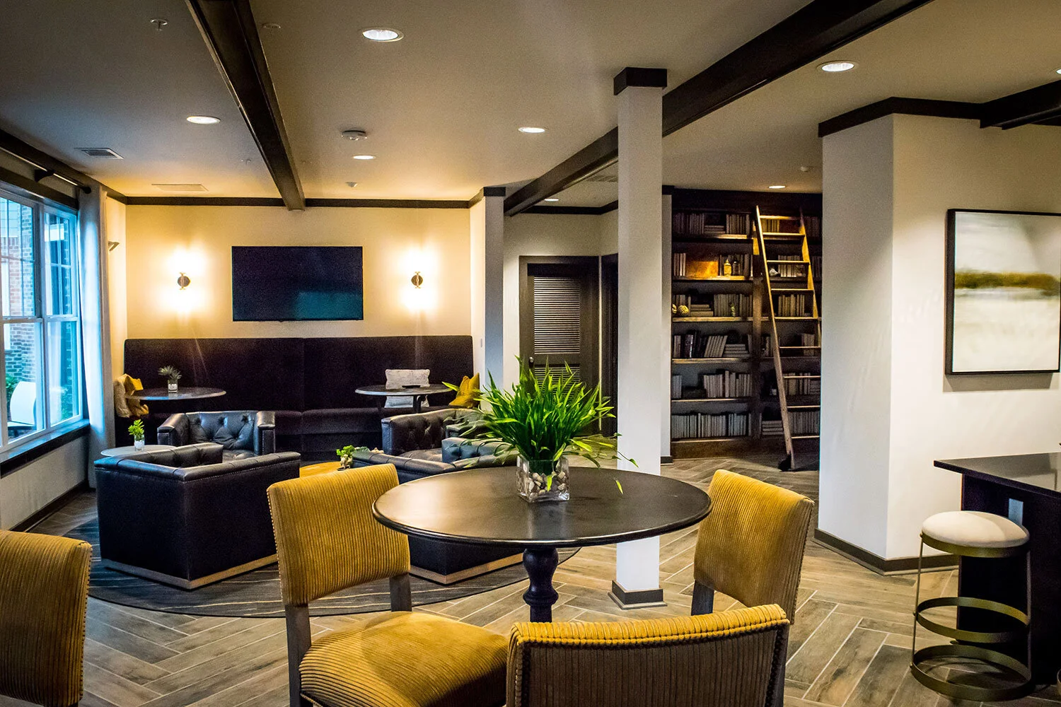 Common room with various seating areas and a large bookshelf in the background at the Riverpoint - Rome, GA