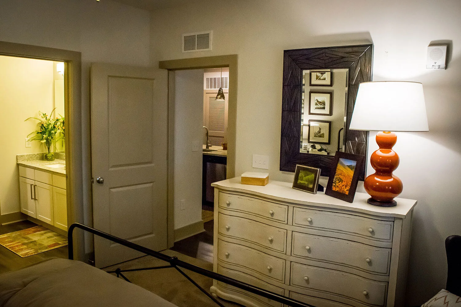 Typical master bedroom found in a multifamily apartment building with dresser and bathroom in the background at Riverpoint - Rome, GA