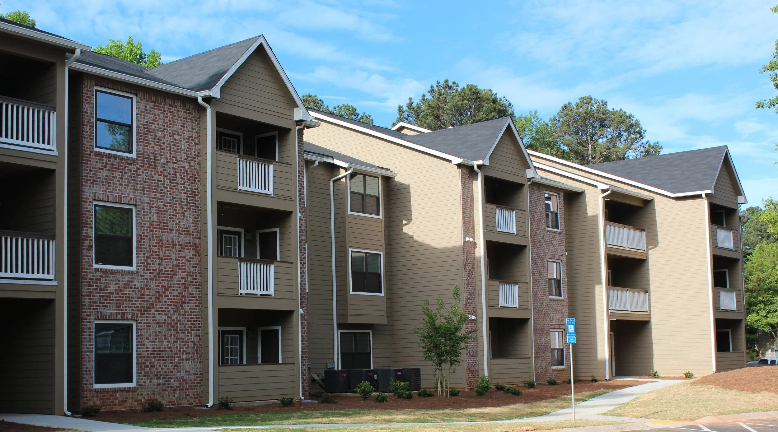 Outdoor shot of a multifamily apartment building with entrances and balconies at the Reserve at Peachtree Corners - Norcross, GA