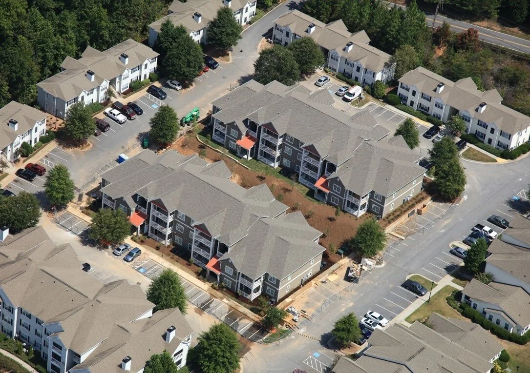Overhead shot of a multifamily apartment complex with parking lot and landscaping at Harbor Creek - Canton, GA