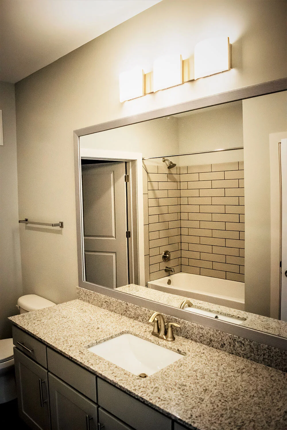 Bathroom with toilet, sink and mirror in a typical multifamily complex unit at City of Refuge - Atlanta, GA