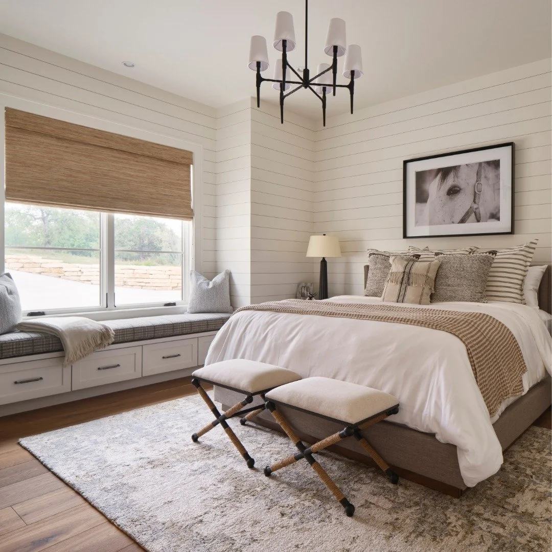 A cozy guest bedroom layered in thoughtful textures. 
 
Horizontal penny-gap paneling wraps the entire room in a soft, continuous texture, setting the tone for a contemporary farmhouse aesthetic. A generous window seat anchors the space, offering the
