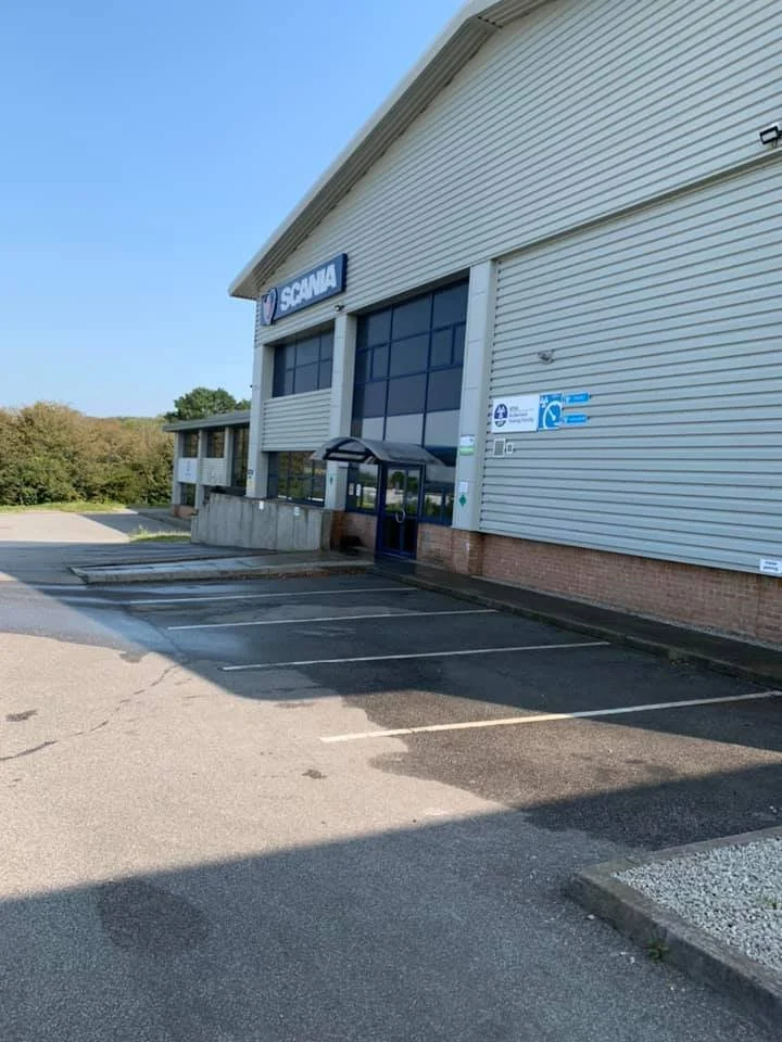 Empty parking lot in front of a Scania building on a sunny day.