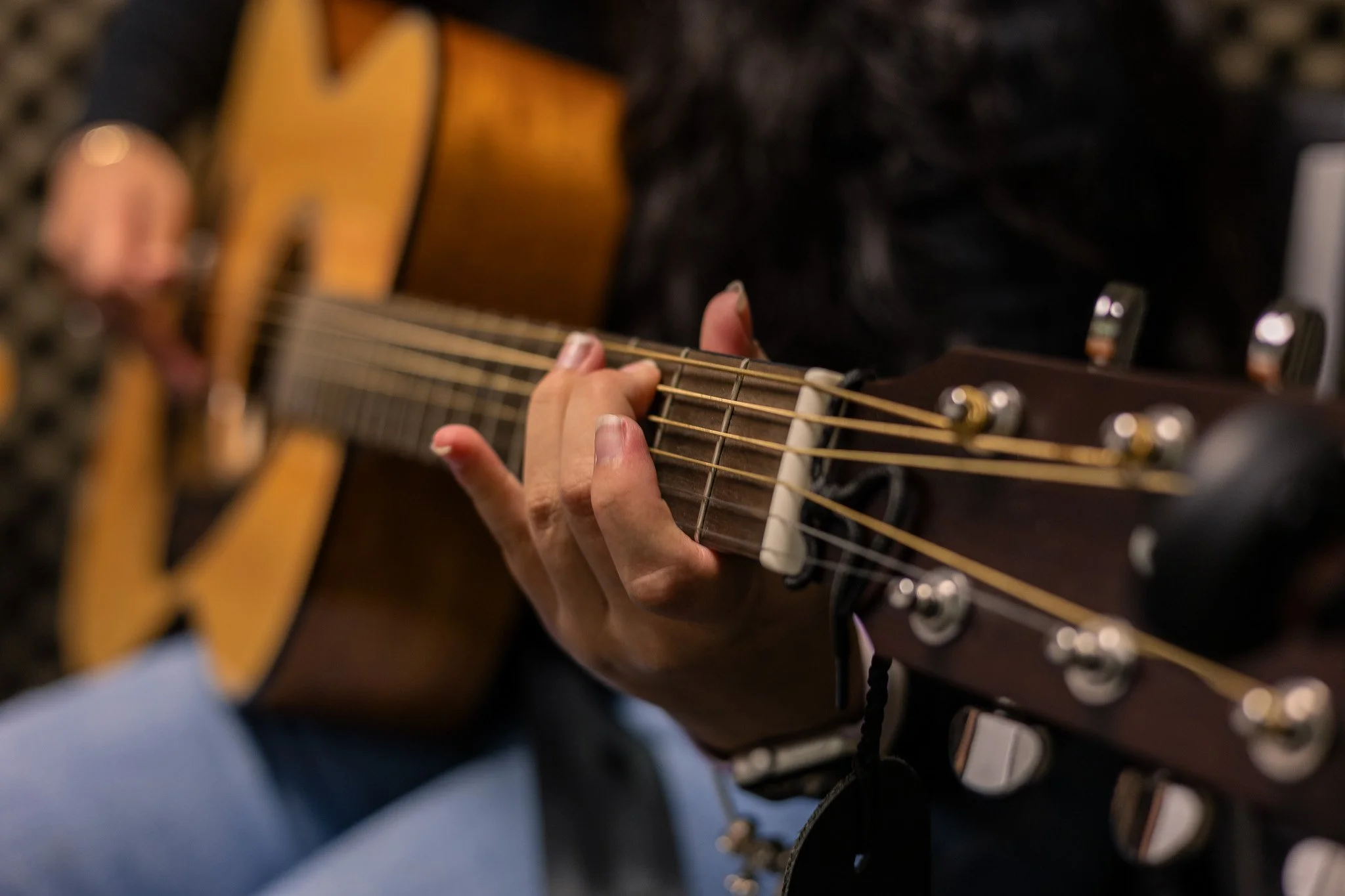 close up of hand holding neck of guitar