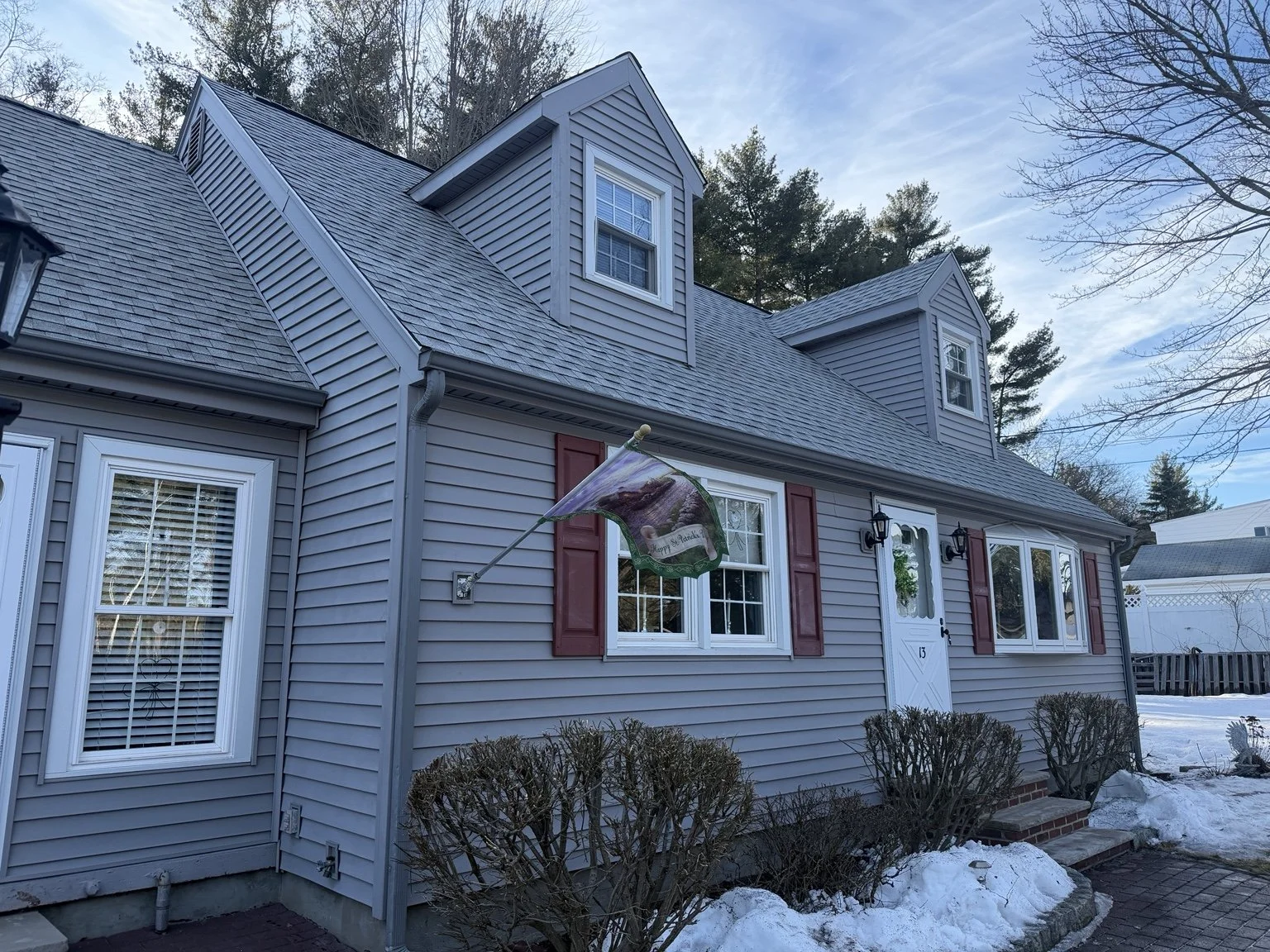 Completed Cape-style home exterior showing the finished roofline, eaves, and gutters.