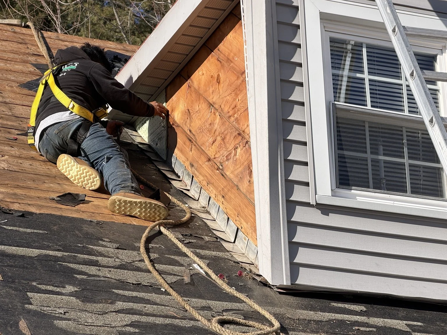 King Construction roofer completing detailed exterior roof work near a window.