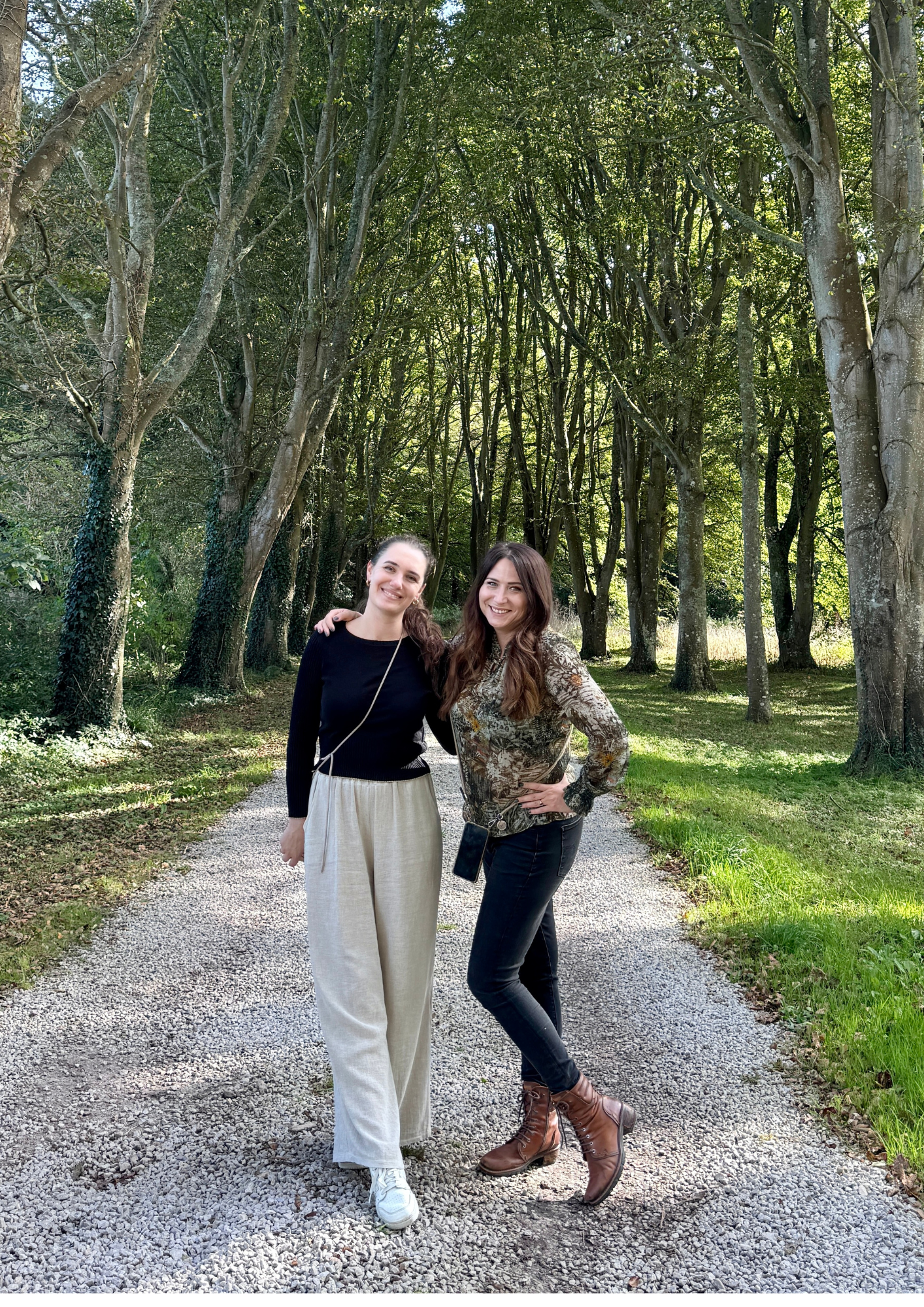 Two coliving professionnals standing on a gravel path in a wooded area, smiling and posing for a photo together for their coliving consulting business.