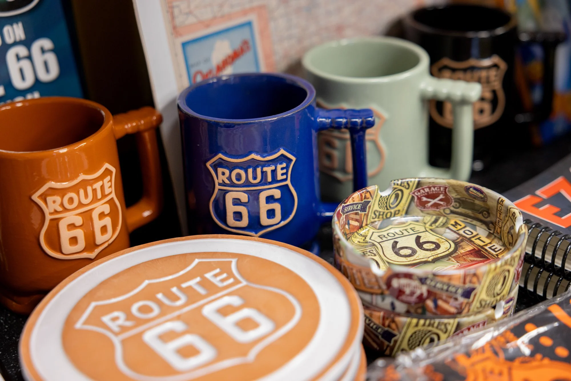 Collection of Route 66 themed mugs, an ashtray, and a decorative plate on a table.