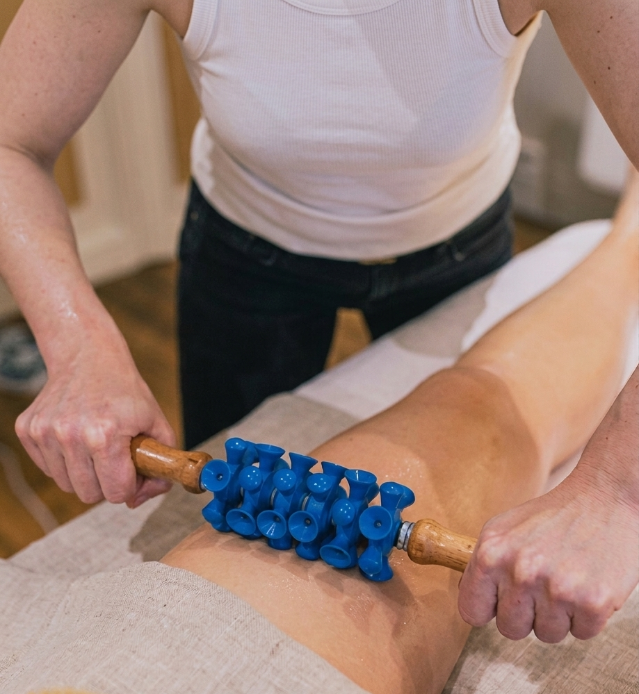 Une femme reçoit un massage avec un rouleau en caoutchouc bleu sur la cuisse.