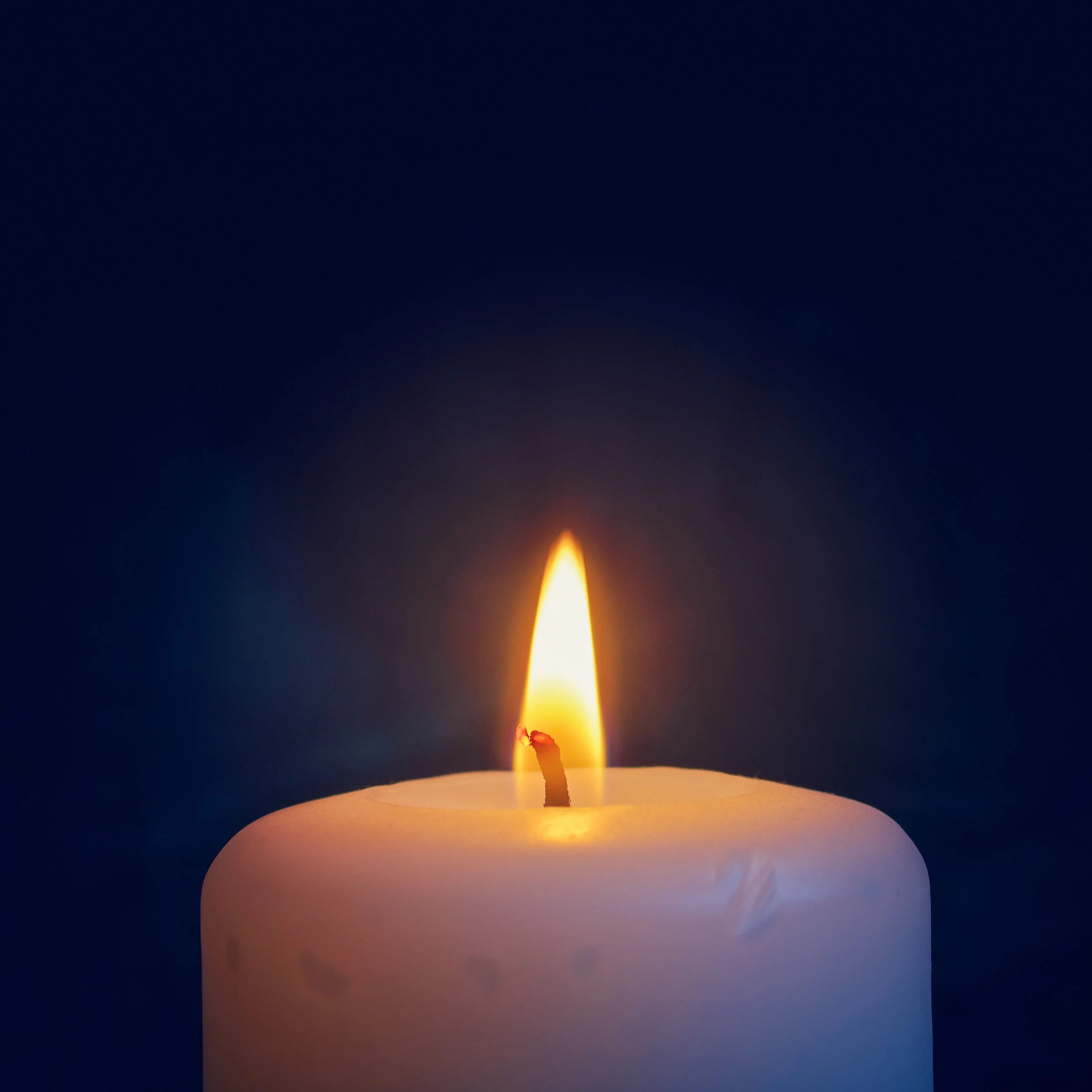 Single candle burning in the darkness, symbolizing the Quaker value of simplicity and inward reflection.