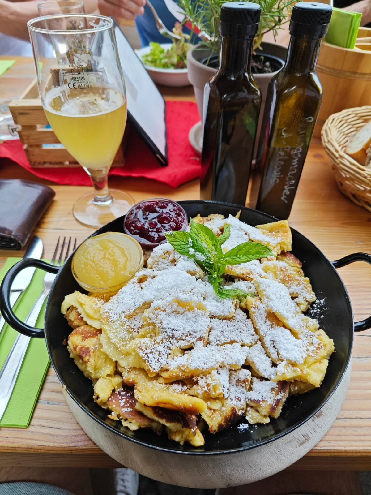 Bergfrühstück mit Spiegelei, Marmelade, Minze, Salz, Pfeffer, Öl, Birne, Bier, Serviette, Messer, Gabel, Gläser, Pflanzen, Holztisch.