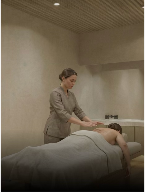 A massage therapist giving a massage to a woman lying face down on a massage table.