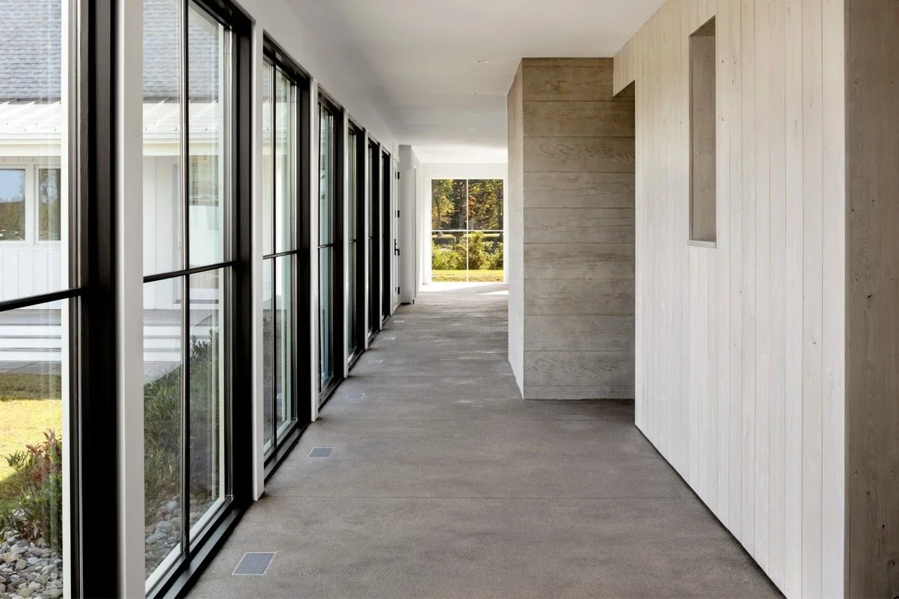 tidewater-farmhouse-chesapeake-concrete-hallway-expansive-windows-queenstown-md-kimmel-architects.webp