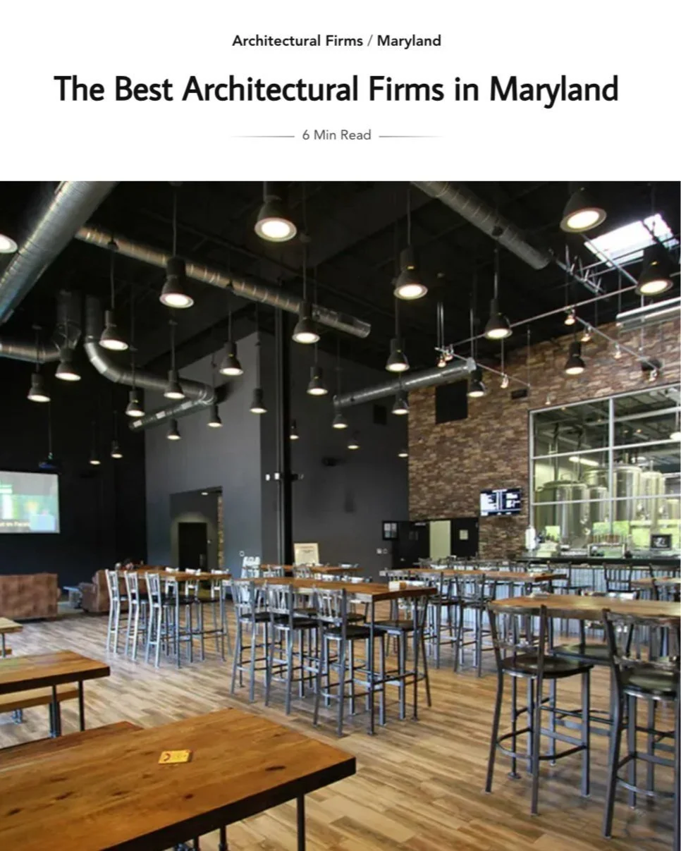 Kimmel Studio Architects press Interior modern restaurant with high ceilings, black walls, exposed ductwork, and multiple tables and chairs, including some high-top tables with metal stools. Large glass windows and brewing tanks.