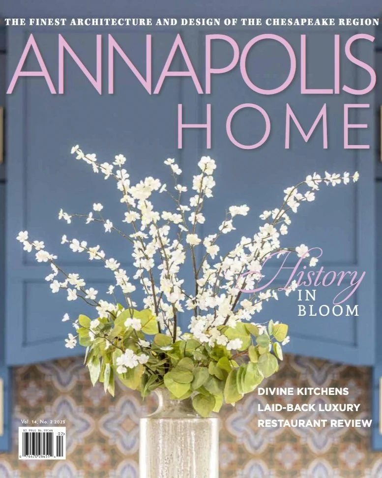 Kimmel Studio Architects Annapolis Home with a flower arrangement of white blossoms and green leaves in a clear glass vase against a blue background.