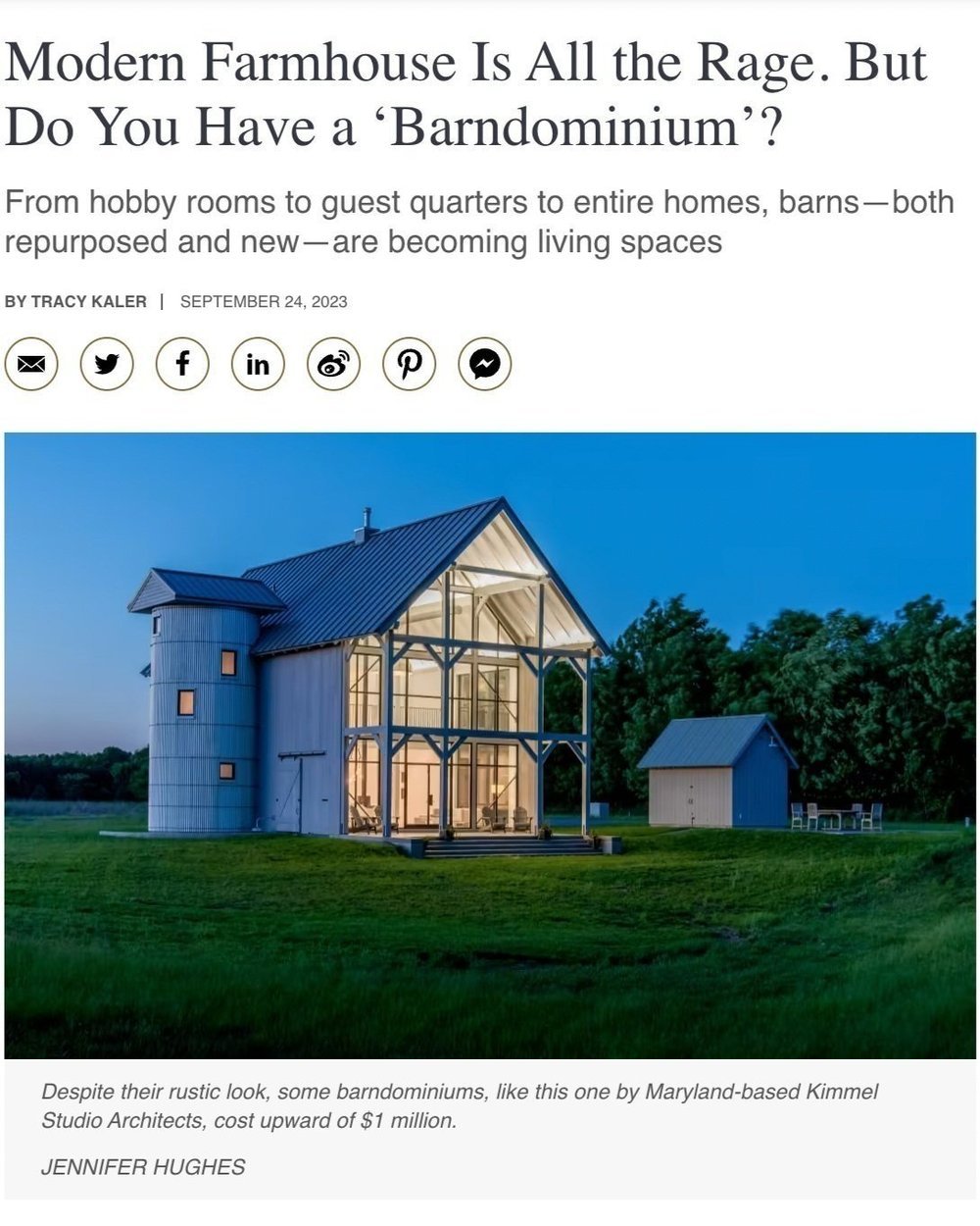 Kimmel Studio Architects press modern barn house with a white exterior, large glass windows, and a gabled roof illuminated at dusk, set in a grassy field with trees in the background.