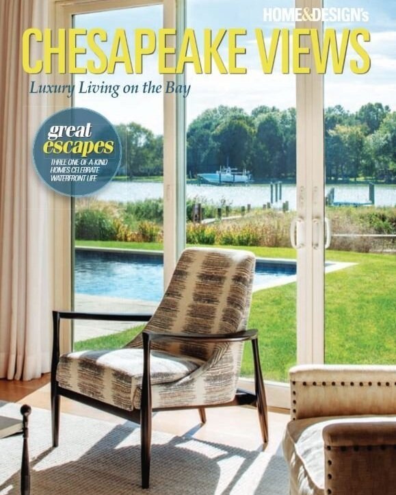 Kimmel Studio Architects Chesapeake Views Magazine Living room with a patterned armchair and a view of a backyard with a pool and a bay seen through large sliding glass doors.
