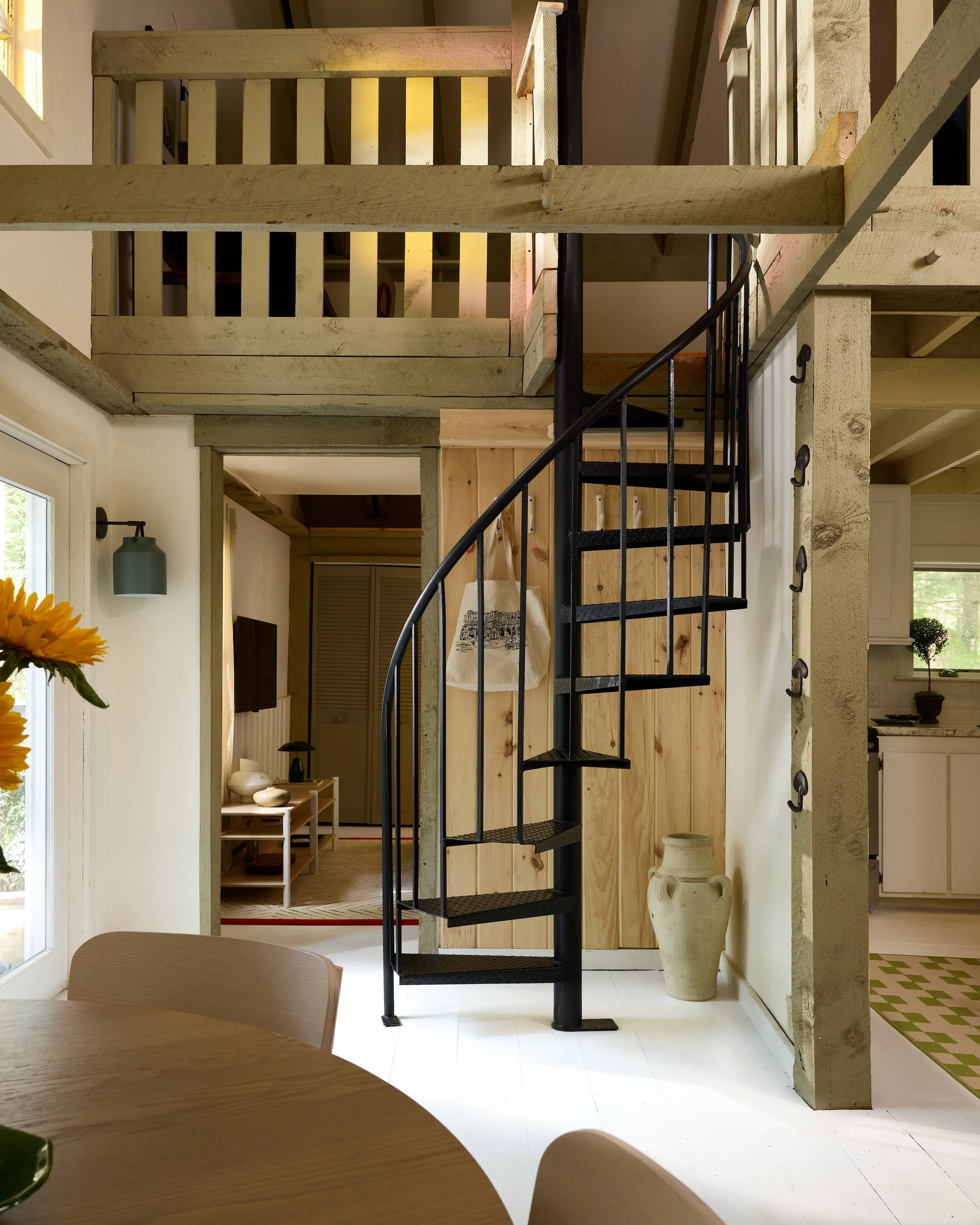 Interior of a home with a black spiral staircase, wooden accents, and a sitting area visible in the background.