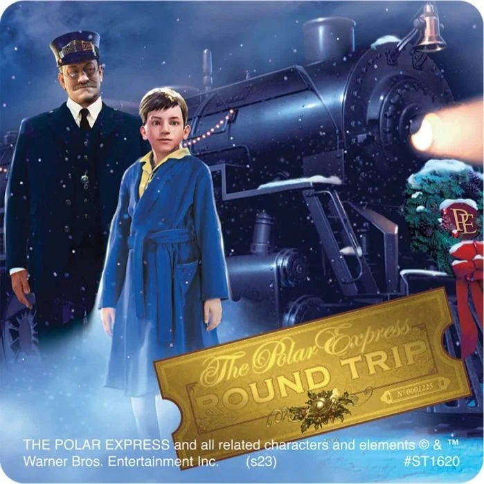 A man and a boy stand in front of a large steam train during a snowy night. The boy is wearing a blue bathrobe, and the man is dressed as a train conductor. There is a wreath with a red bow and a sign reading 'The Polar Express Round Trip' in the foreground.