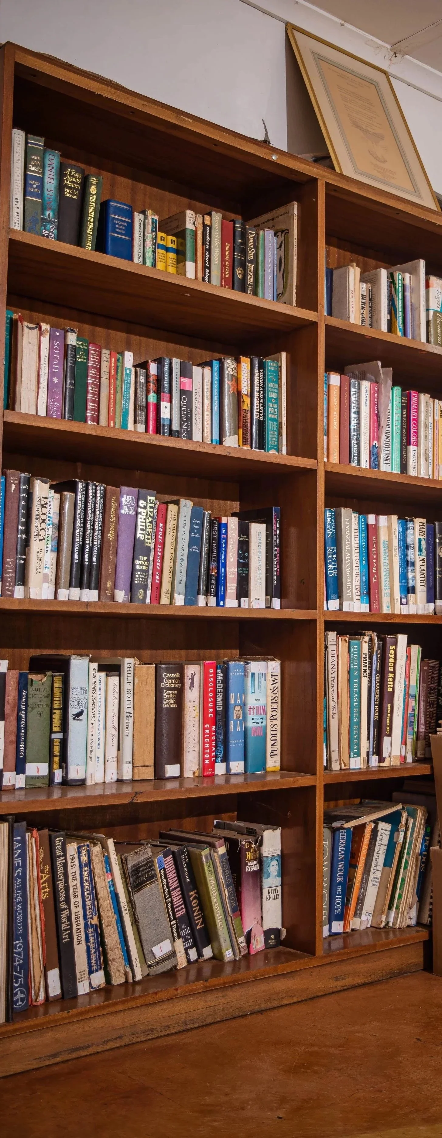 Children sitting on chairs, smiling, and giving thumbs up. One child in the foreground showing a bright smile and wearing a gray shirt with colorful stripes, while another child in the background wearing a face mask and a Lol sticker.