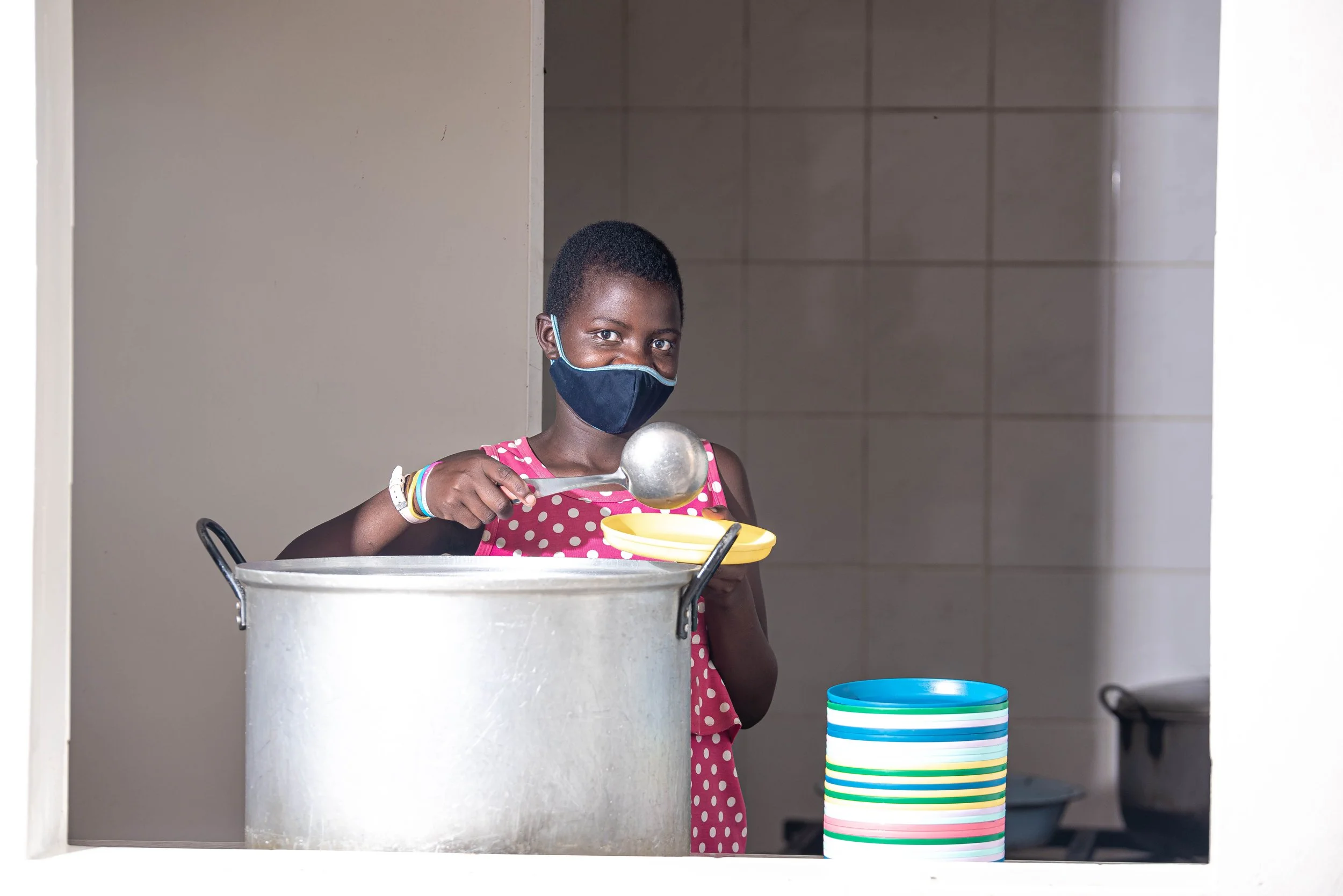 Two young children wearing hair nets and preparing food in a kitchen, chopping vegetables and rolling dough.