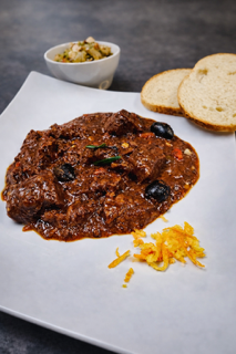 Traditional French La Daube, slow-braised beef in a rich wine sauce with olives and citrus, served at La Crêperie in Granbury.