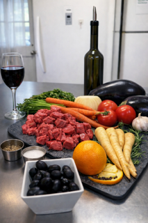 Fresh ingredients prepared for traditional French La Daube, including beef, vegetables, herbs, olives, citrus, and red wine at La Crêperie in Granbury.