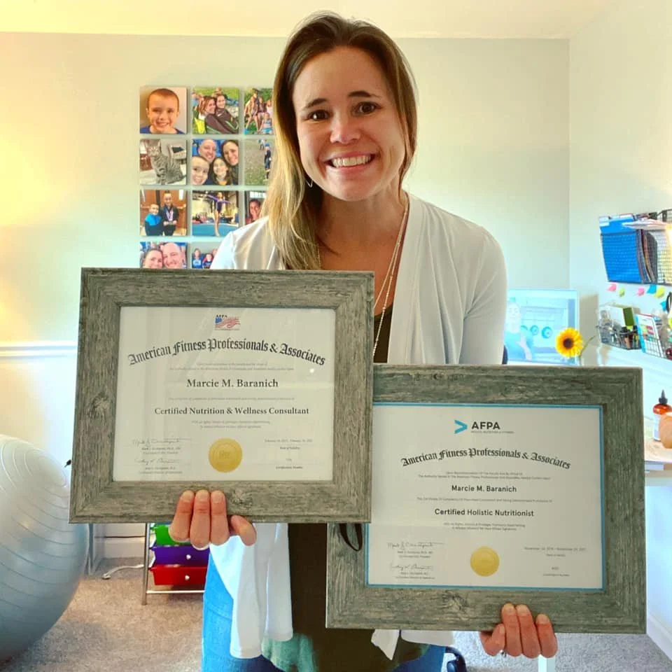 Marcie Baranich, owner of Mattison Digital, holding two framed certificates for nutrition and wellness certification.