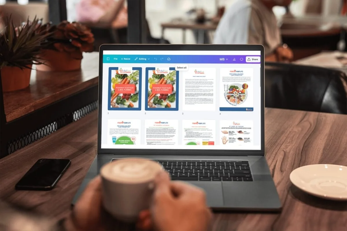 A person holding a coffee cup in front of a laptop in a cafe, with a document editing software open on the laptop screen showing health and nutrition brochures.