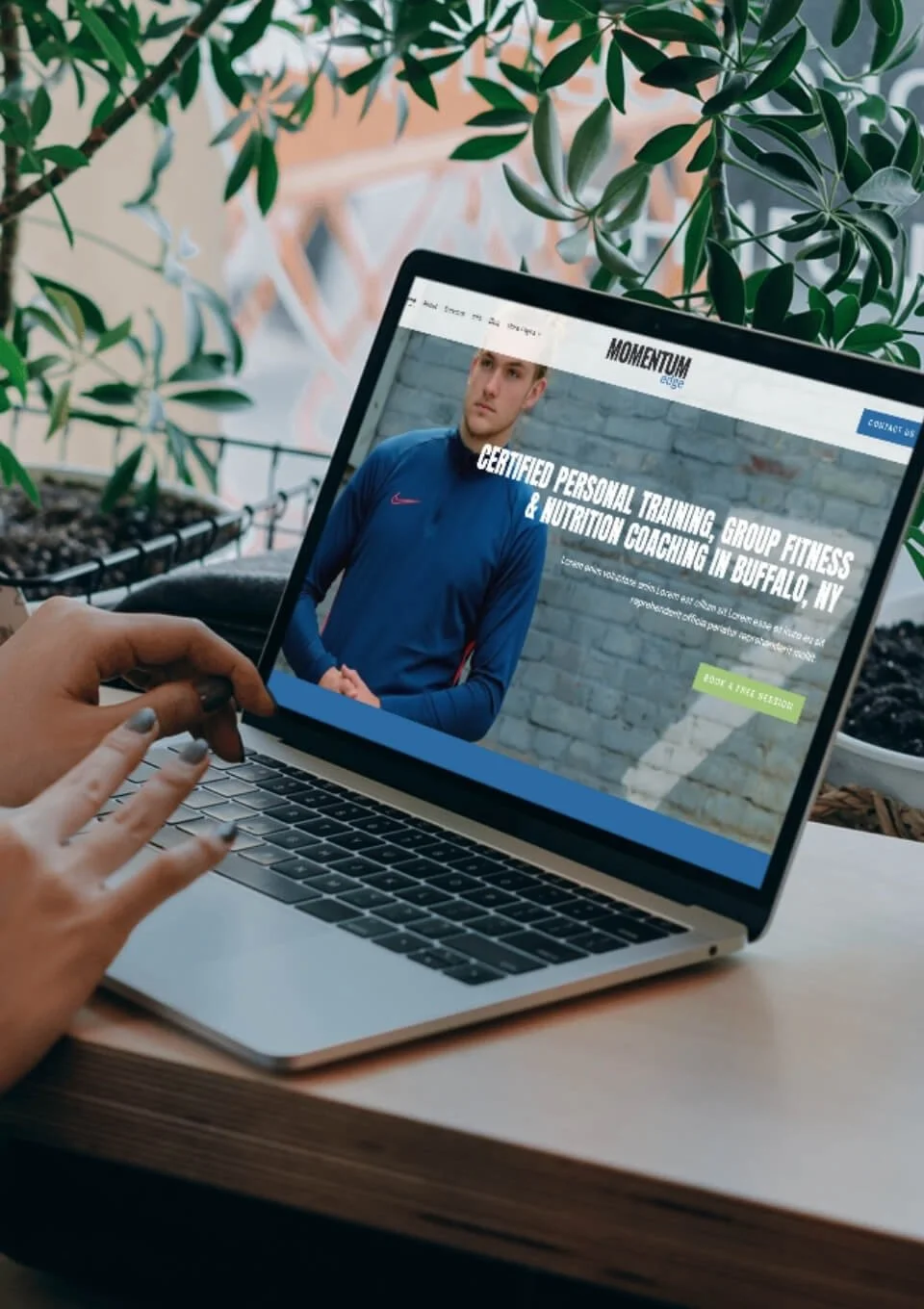 A person using a laptop displays the Momentum Edge template with information about personal training and nutrition coaching in Buffalo, NY.
