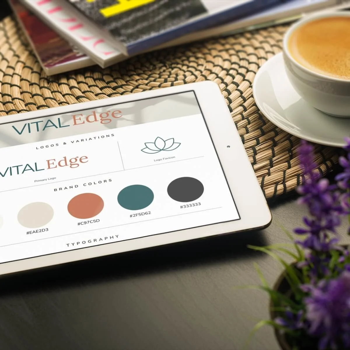 Digital tablet displaying a branding design for 'VITAL Edge' with logo options, brand colors, and typography details, placed on a table nearby a cup of coffee.