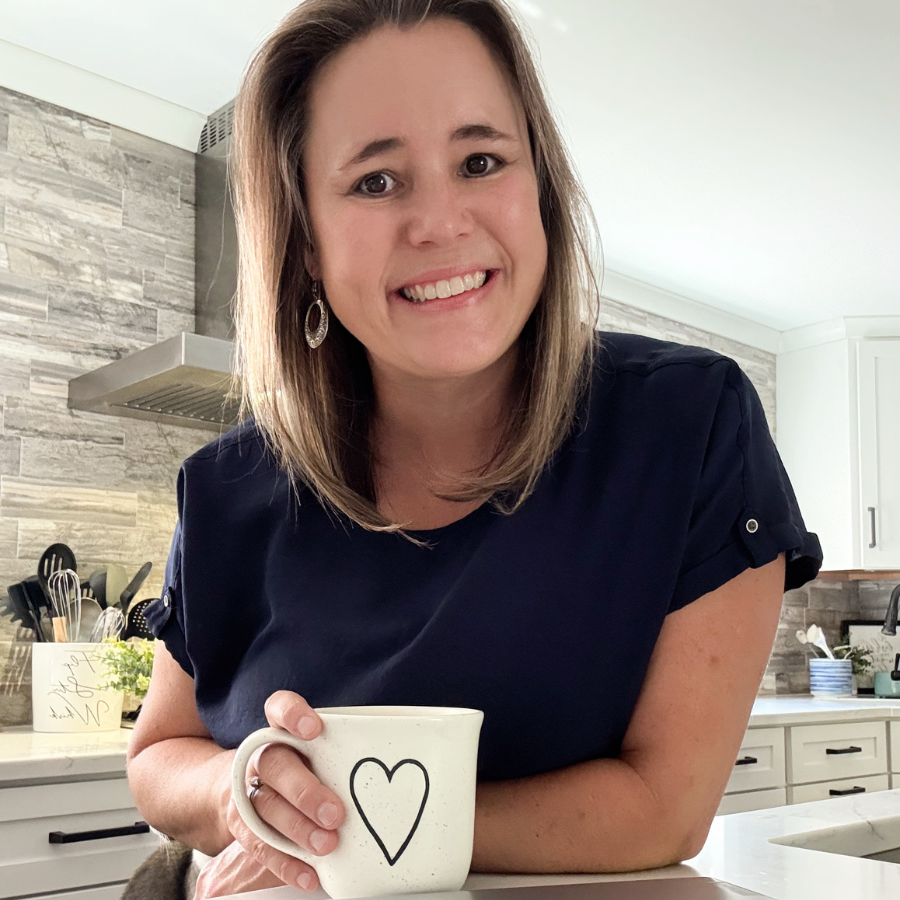 Marcie Baranich, owner of Mattison Digital, holding a mug with a heart on it in a modern kitchen.