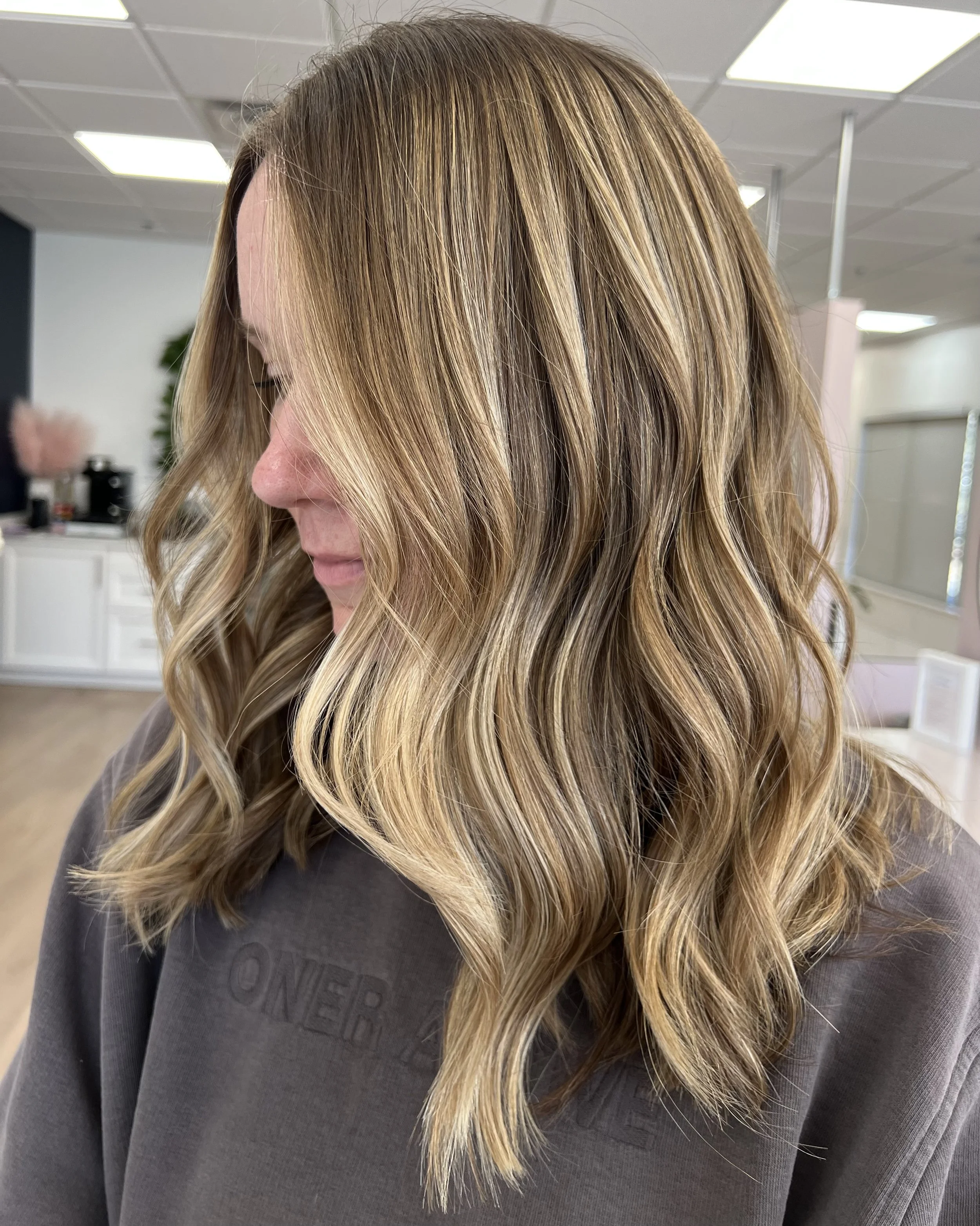 Close-up of a woman with long, wavy blonde hair in an indoor setting.