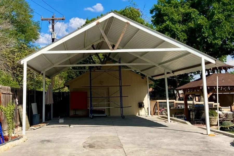 Gable roof metal carport structure providing covered parking and patio space